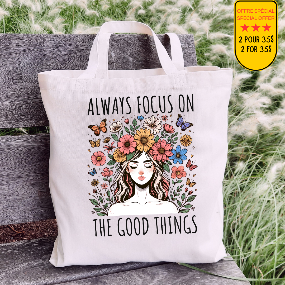 Sac fourre-tout en coton de couleur naturel de 15 x 16 pouces avec un design boho d'une femme entourée de fleurs colorées et de papillons, accompagnée du texte “Always Focus on the Good Things”.
