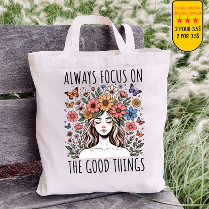 Sac fourre-tout en coton de couleur naturel de 15 x 16 pouces avec un design boho d'une femme entourée de fleurs colorées et de papillons, accompagnée du texte “Always Focus on the Good Things”.