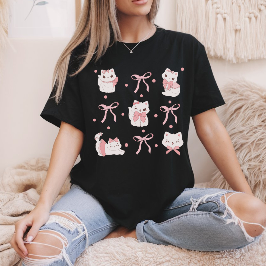 T-shirt noir avec illustration de quatre chats noirs portant des nœuds roses style coquette, impression DTF sur coton doux."