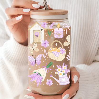 Verre à café glacé décoré de brins de lavande violets et d'un papillon, avec couvercle en bambou et paille.