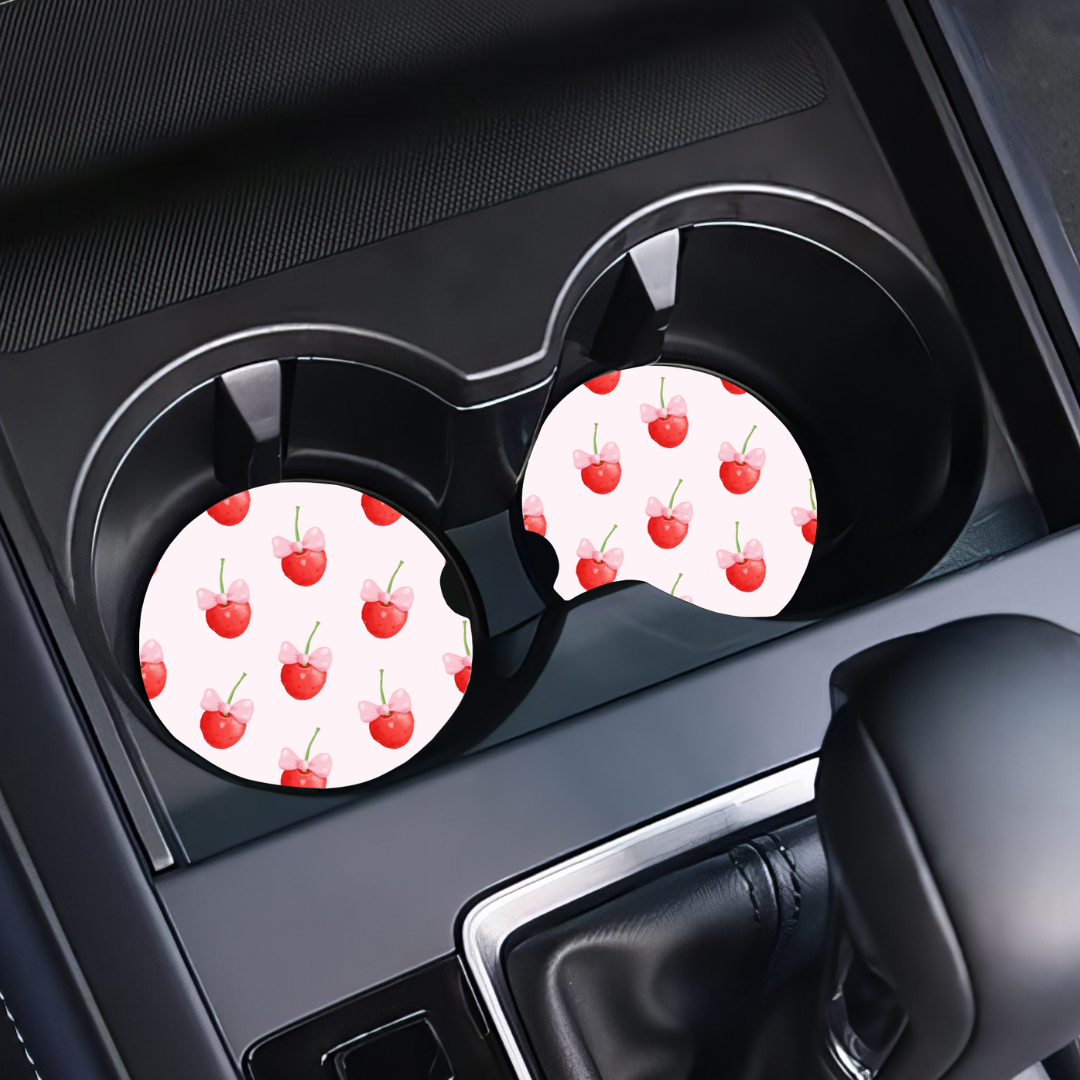 Sous-verres motif cerises coquettes installés dans les portes-gobelets d'une voiture