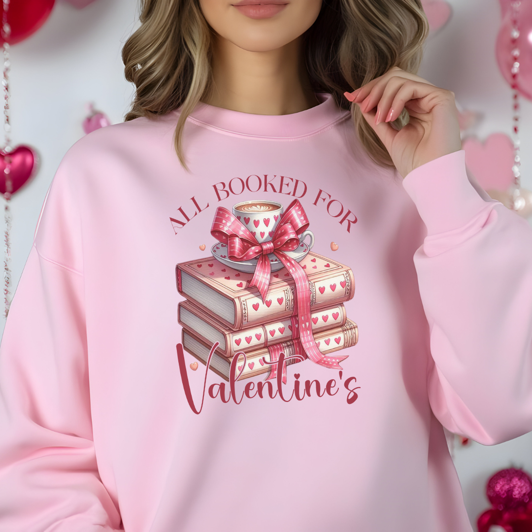 Mannequin portant un sweatshirt rose avec un design  “All Booked for Valentine’s”, illustré par une pile de livres décorés de cœurs et une tasse de café, style romantique et cosy.