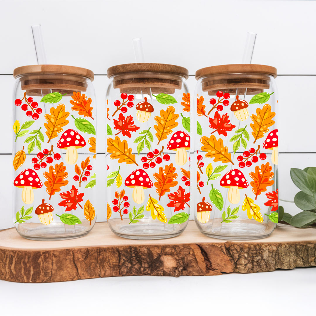 Verre à café glacé transparent de 16 oz orné de motifs automnaux détaillés de champignons sauvages, glands et feuilles rousses, présenté avec son couvercle en bambou et sa paille en verre.