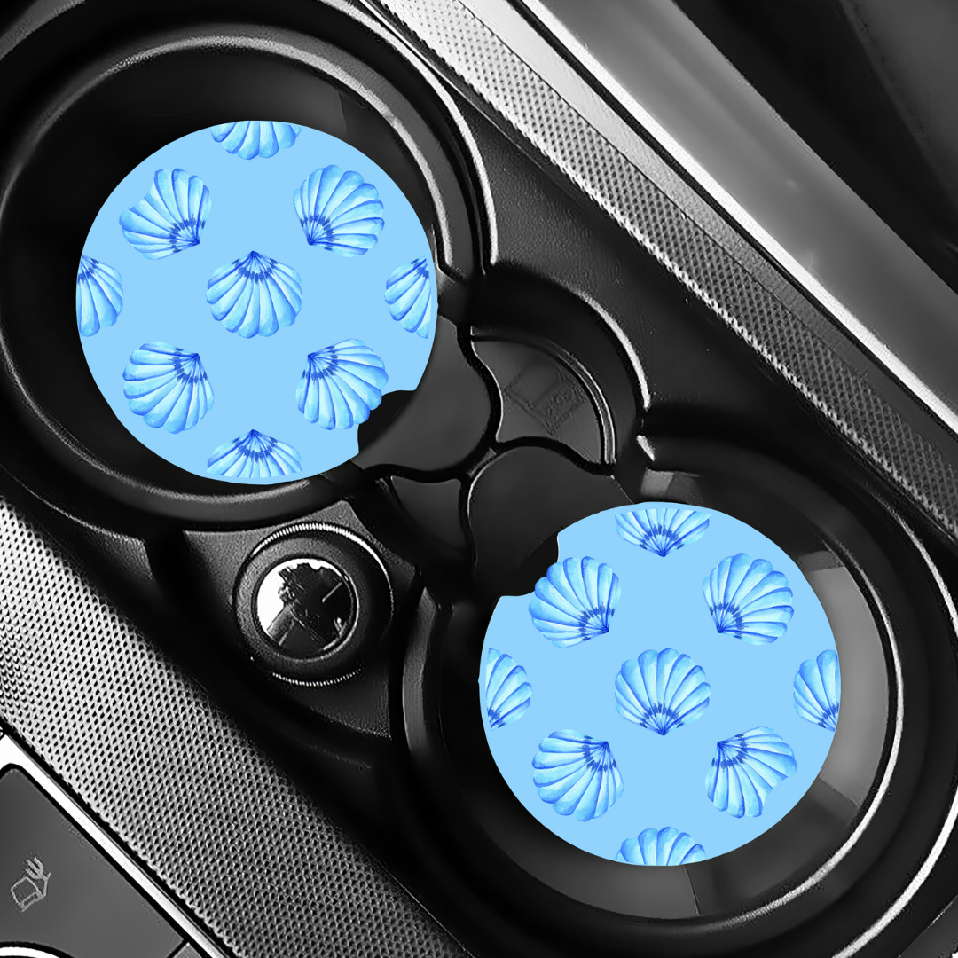Sous-verres motif coquillages installés dans les porte-gobelets d'un véhicule pour une déco estivale.
