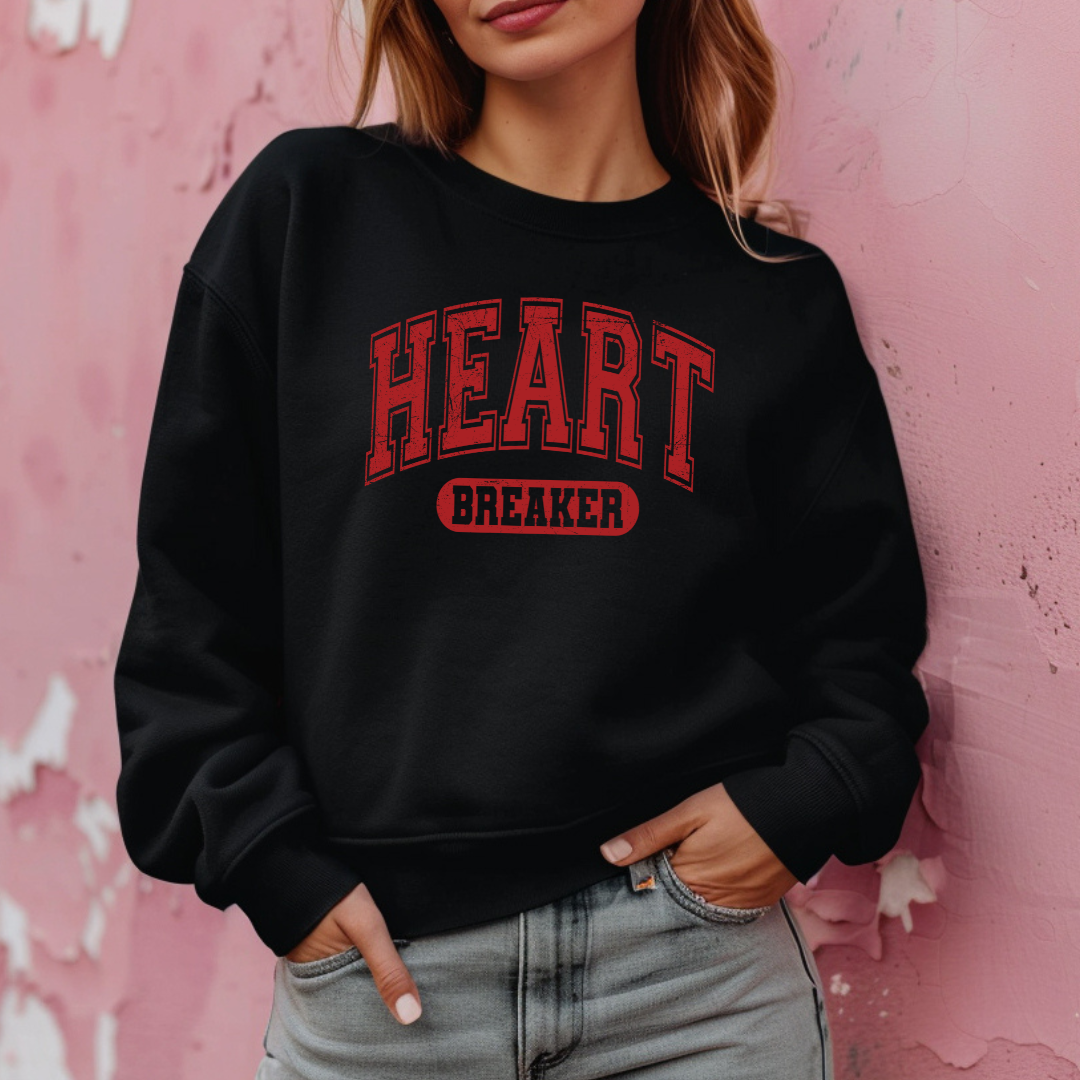 Sweatshirt  Gildan noir avec un design de St-Valentin “Heart Breaker” en lettres rouges style varsity, imprimé audacieux et effet légèrement usé.