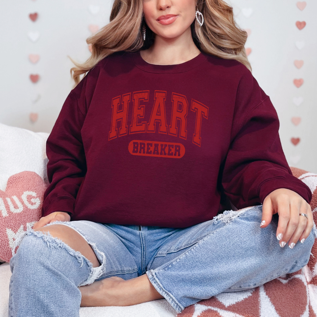 Sweatshirt  Gildan Bourgogne avec un design de St-Valentin “Heart Breaker” en lettres rouges style varsity, imprimé audacieux et effet légèrement usé.