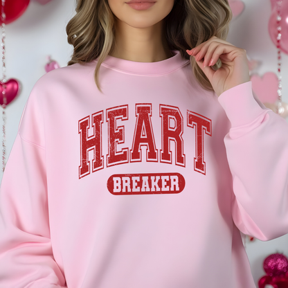 Sweatshirt  Gildan Rose pâle avec le design “Heart Breaker” en lettres rouges style varsity, imprimé audacieux et effet légèrement usé.