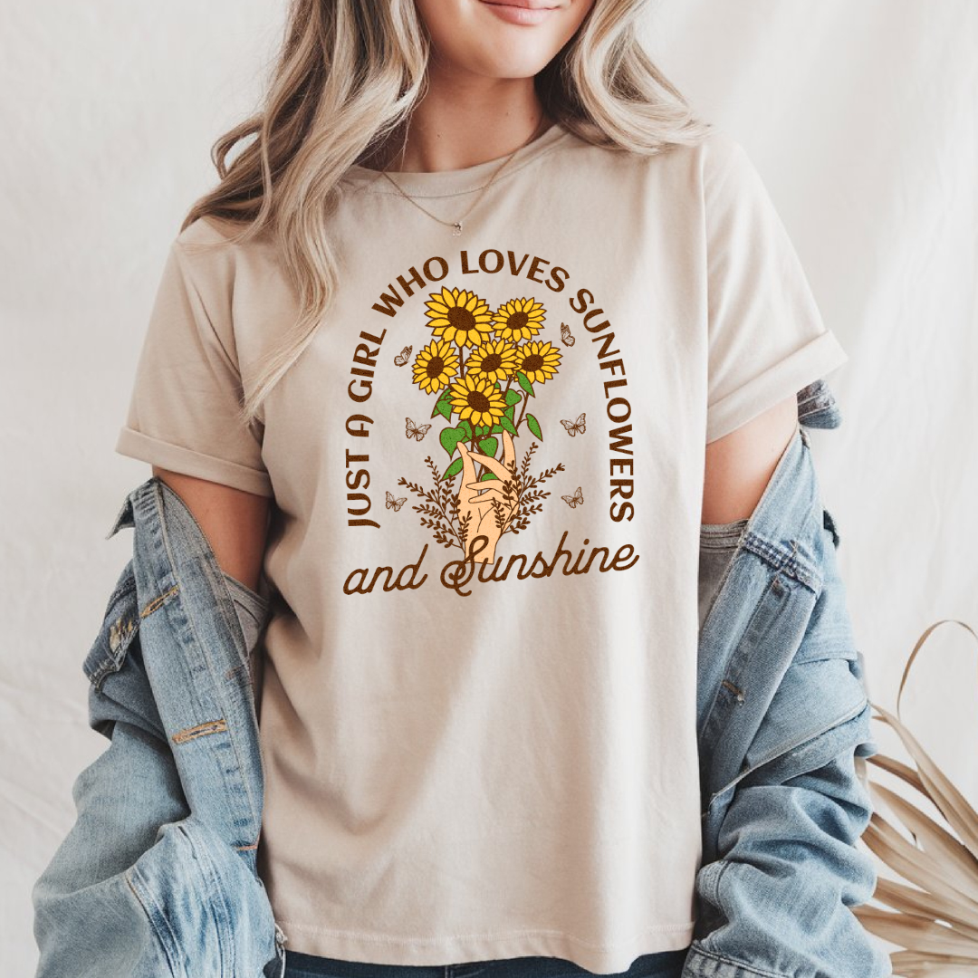 Femme portant un t-shirt beige style bohème avec un graphisme de tournesols et le texte "Just a Girl Who Loves Sunflowers and Sunshine", agencé avec une veste en jean bleue.