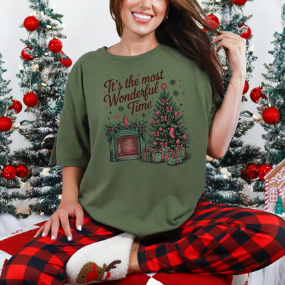 T-shirt de couleur vert militaire avec Illustration festive d’un sapin décoré et d’une cheminée illuminée, ambiance vintage et chaleureuse pour Noël.
