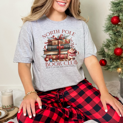 T-shirt Gildan gris athlétique avec un imprimé Livres de Noël empilés attachés d'un ruban rouge accompagnés d'une tasse de chocolat chaud. Ambiance cozy festive – parfait pour les fans de lecture !