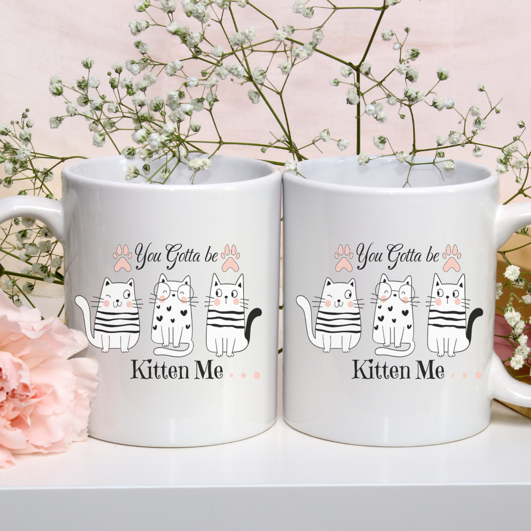 Tasse blanche 15 oz avec l'inscription humoristique "You Gotta be Kitten Me" et des illustrations de chats mignons dans différentes positions amusantes.