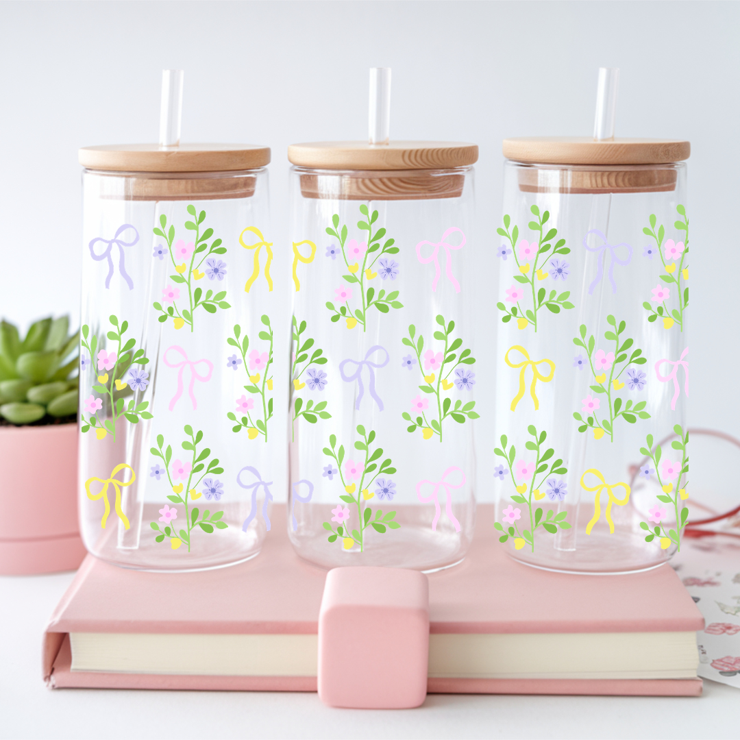 Verre à café glacé transparent de 16 oz orné de motifs de bouquets de fleurs et de rubans style coquette jaune, mauve et rose, avec couvercle en bambou et paille en verre.