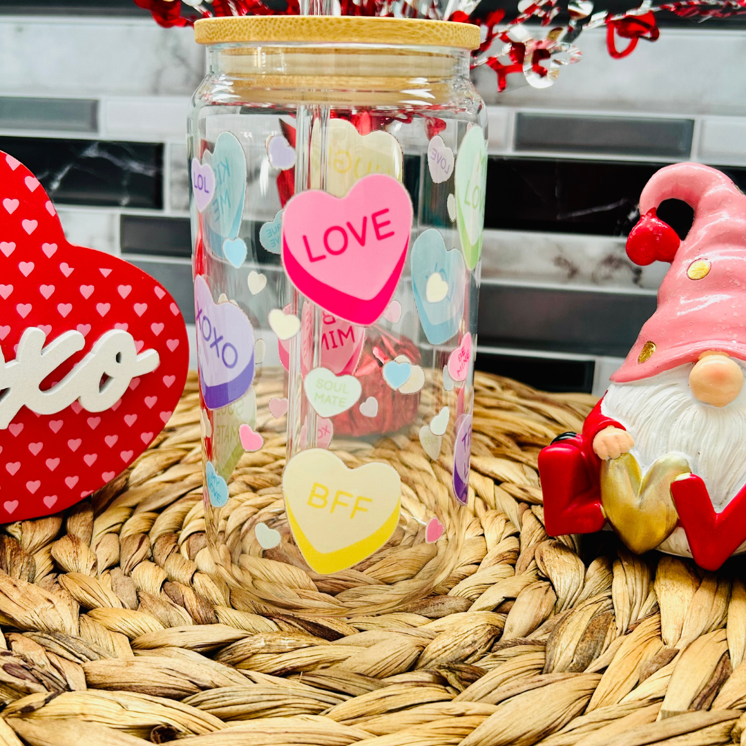 Verre à café glacé Libbey 16 oz avec motifs de cœurs de bonbons multicolores (Conversation Hearts) et messages d'amour, incluant couvercle en bambou et paille.